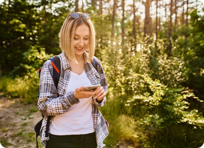 female looking at her phone in the woods